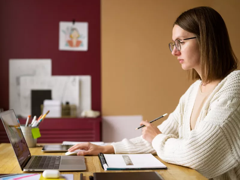 Woman viewing a laptop screen while working with a pencil and notebook; connects to Fantastic Writing Tips and How to Find Them.